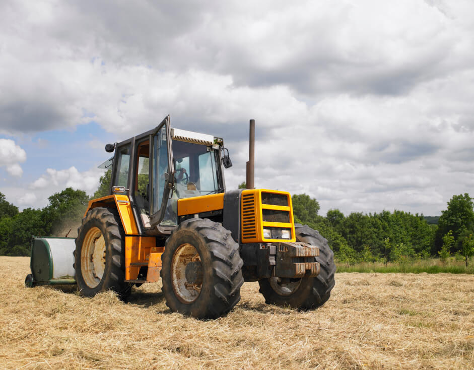 Farm tractor working in a field, showing why are diesel engines used for heavy equipment due to their torque and fuel efficiency.