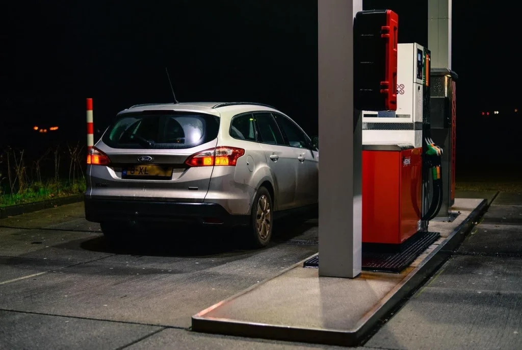Silver car refueling at night, showing rising diesel and gasoline tax impact.