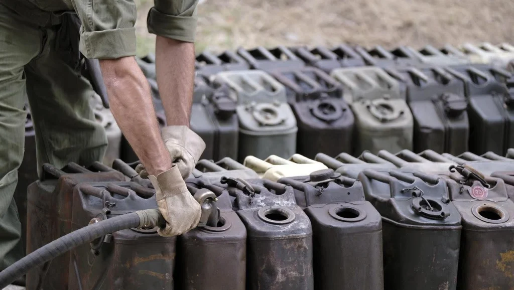 Worker refilling diesel jerry cans