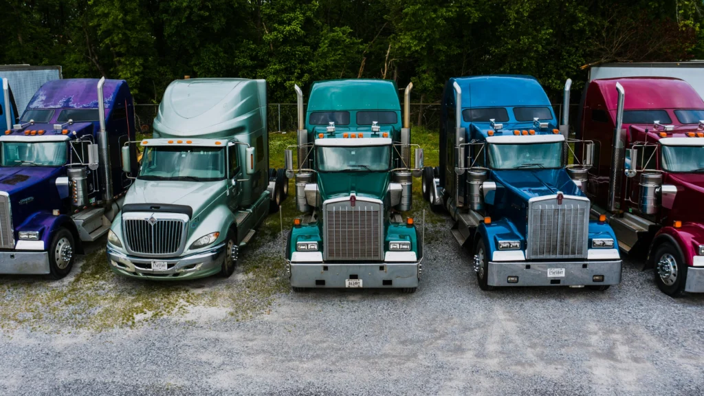 Fleet of colorful semi trucks parked at a logistics yard for freight delivery.