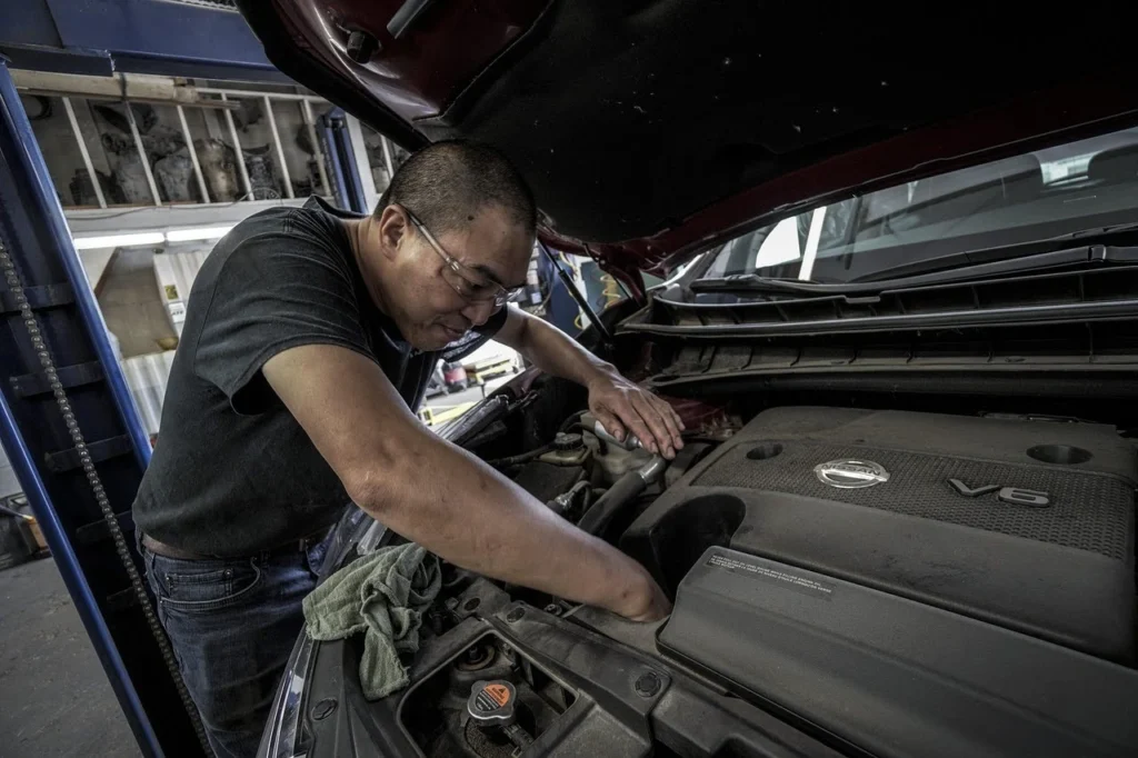 Mechanic inspecting a diesel engine under the hood during routine maintenance and repair