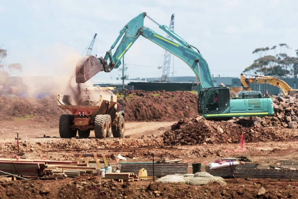 Fuel downtime cost impact on construction site with excavator and dump truck paused during earthmoving operations